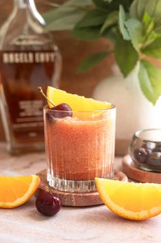 an orange and cherries garnish the top of a glass with a drink in it