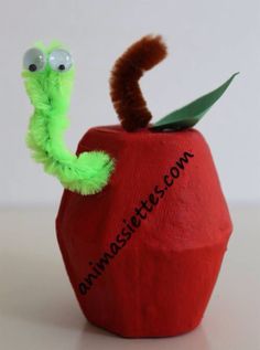 a paper mache apple with a worm sticking out of it's side and eyes