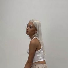 A photograph of a young Asian woman with tan skin and white hair, wearing a white cropped tank top. She faces three quarters left in front of a plain white background. Tan With Platinum Blonde Hair, Platinum Hair On Tan Skin, Platinum Blonde Olive Skin, Platinum Hair Olive Skin, Platinum Blonde Tan Skin, Platinum Blonde Hair On Tan Skin, Platinum Blonde Hair Tan Skin, Tan Skin White Hair, Tan With Blonde Hair