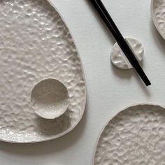 chopsticks and plates on a white surface with black ink in the middle one is empty