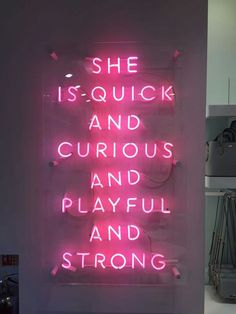 a pink neon sign that says she is quick and curious and playful and strong,