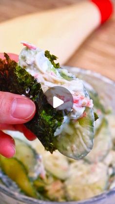 a person holding up a piece of broccoli in a bowl with other food items