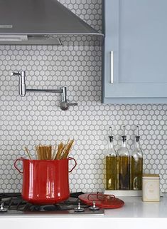 a red pot sitting on top of a stove next to a wall mounted oven hood