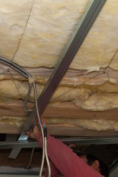 a man is working on the ceiling in his garage with wires attached to the roof