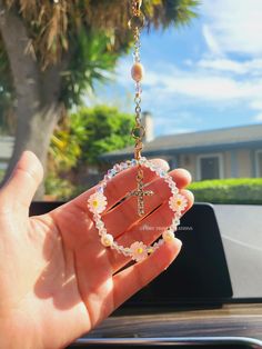 a person is holding up a rosary with flowers and beads on it in their hand