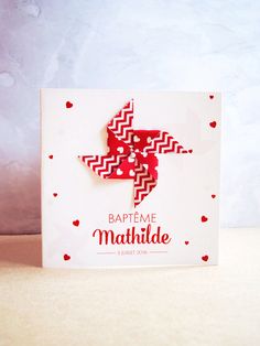 a red and white paper cut out of the shape of a bird on top of a card