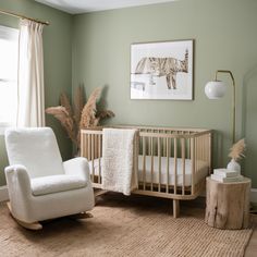 a baby's room with green walls and white furniture