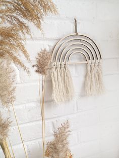 a white brick wall with dried plants and a wind chime hanging from it's side