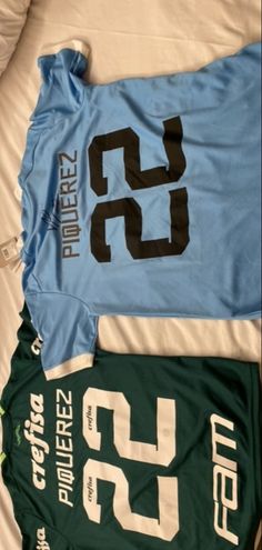 three jerseys laying next to each other on top of a bed in a room with white sheets