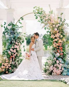 a bride and groom standing under an arch with flowers