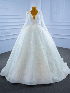 a white wedding dress with long sleeves and sequins on the skirt is displayed