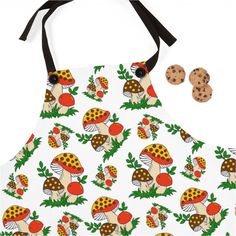 an apron with mushrooms and leaves on it, next to two chocolate chip cookies