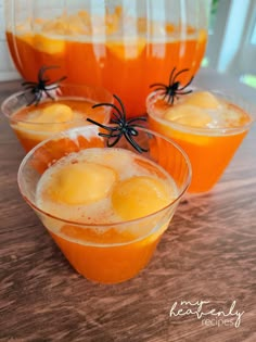 three glasses filled with orange juice and spider webs on the rim, sitting on a table