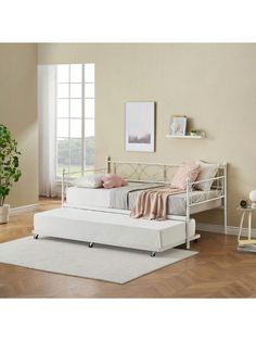 a white daybed sitting on top of a hard wood floor next to a window