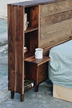 a bed with a wooden headboard next to a night stand on concrete flooring