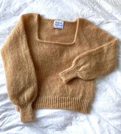 a brown sweater laying on top of a bed