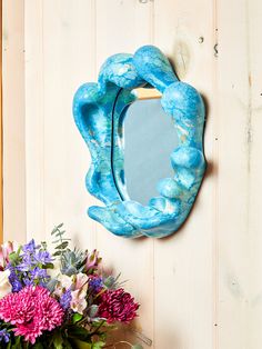 a blue mirror sitting on top of a wall next to a vase filled with flowers