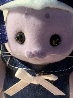 a close up of a stuffed animal wearing a blue hat and sweater with a bow tie