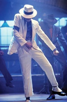 a man in white suit and hat dancing on stage