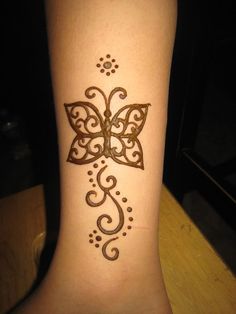 a woman's foot with a henna tattoo on her left leg and a butterfly design on the ankle