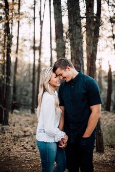 a man and woman standing next to each other in the woods