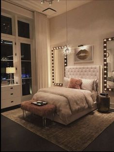 a bedroom with a large bed and lights on the wall above it, along with an ottoman