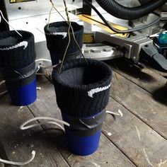 three blue cups sitting on top of a wooden table next to an electrical wire and wires