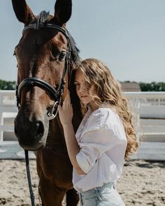 a woman standing next to a brown horse