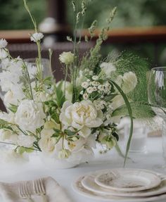 a table set with white flowers and silverware