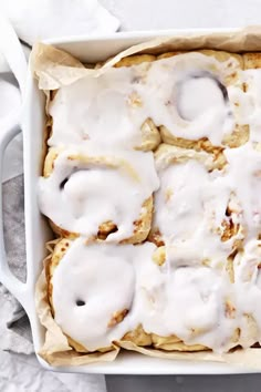 an image of cinnamon rolls with icing in a white dish on a table and text overlay that reads dairy free cinnamon rolls