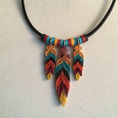 a multicolored necklace is hanging from a black cord on a white table top