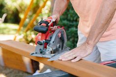 a man using a circular saw to cut wood with a mitt on a bench