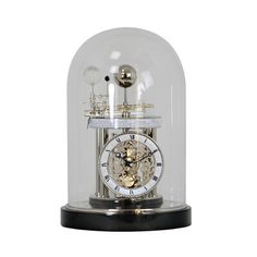 a small clock under a glass dome on a black base with gold trimmings