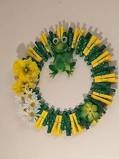 a green frog sitting on top of a wreath made out of legos and flowers