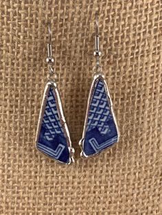 two blue and white earrings on top of a piece of cloth