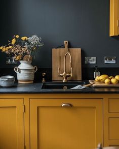 a kitchen with yellow cabinets and black counter tops is pictured in this image, there are lemons on the counter