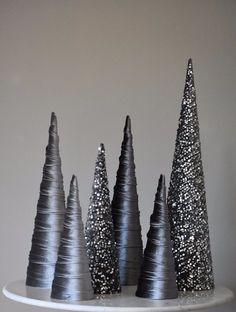 three black and silver christmas trees sitting on top of a white cake plate with confetti sprinkles