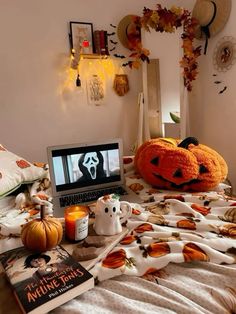 a laptop computer sitting on top of a bed covered in pumpkins and other decorations