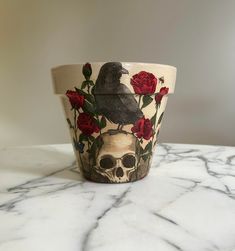 a cup with roses and a bird painted on it sitting on a marble counter top