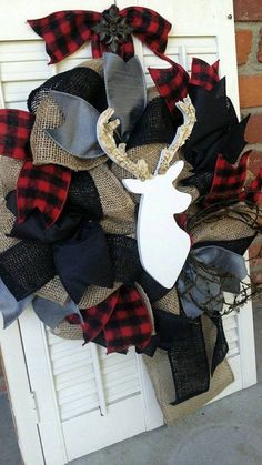 a wreath with a deer head and antlers is hanging on the front door,