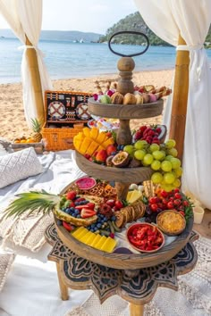 a tiered tray filled with lots of food on top of a table next to the ocean