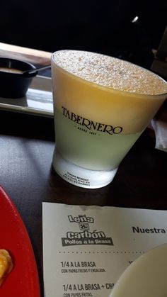 a table topped with a plate of food next to a glass filled with liquid on top of it