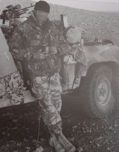 a man in camouflage standing next to an army vehicle