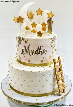 a three tiered cake decorated with gold stars and the number one on it's side