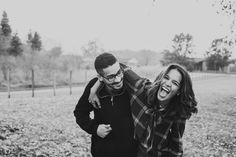 a man and woman laughing while standing in the grass