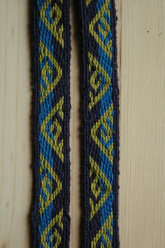 two blue and yellow bracelets sitting on top of a wooden table