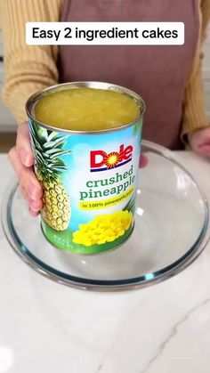 a person holding a can of pineapple cake on top of a glass platter