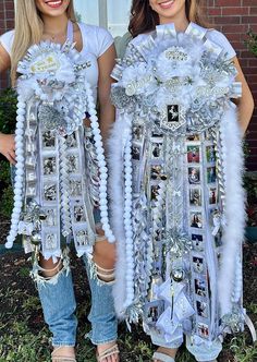 two women in white outfits holding up some decorations