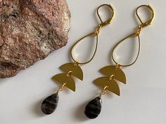 two pairs of earrings sitting next to a rock