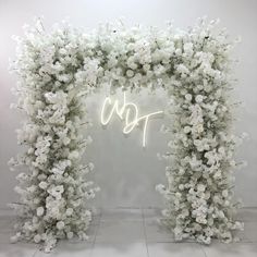 a white floral archway with the word love spelled in neon letters on it's side